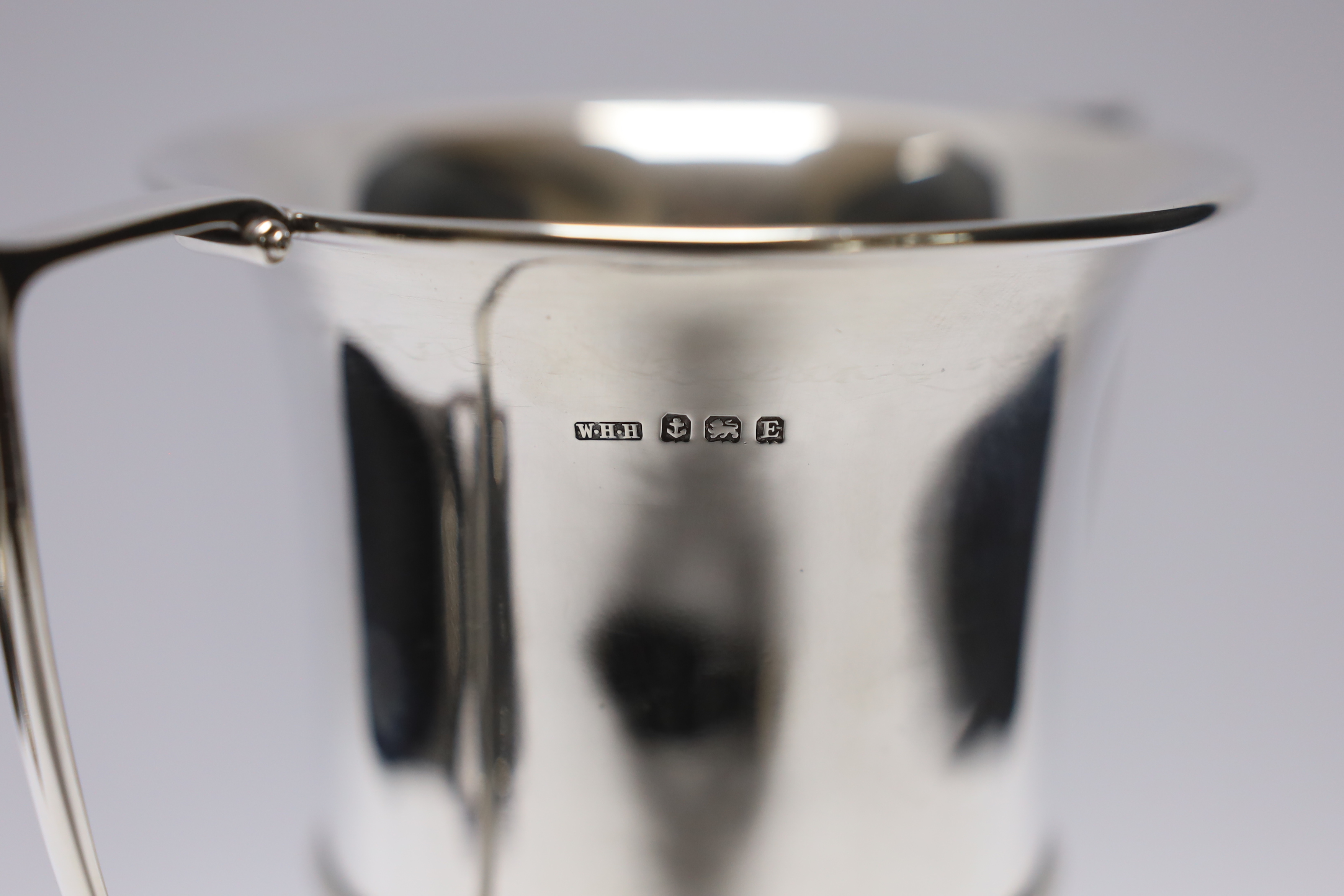 A George V unengraved silver two handled trophy cup, W H Haseler Ltd, Birmingham, 1929, height 17.6cm, 9.5oz, on an ebonised socle.